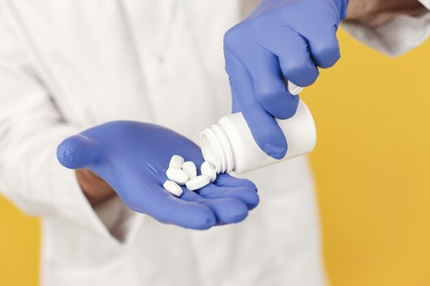 Doctor en medicina sonriente con pastillas. Aislado. Hombre en guantes azules.
