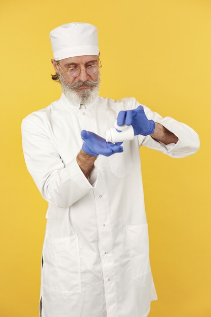 Doctor en medicina sonriente con pastillas. Aislado. Hombre en guantes azules.