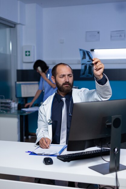 Doctor mirando escaneo de rayos X en la mano para diagnóstico médico