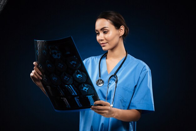 Doctor morena en uniforme mirando la imagen de rayos x