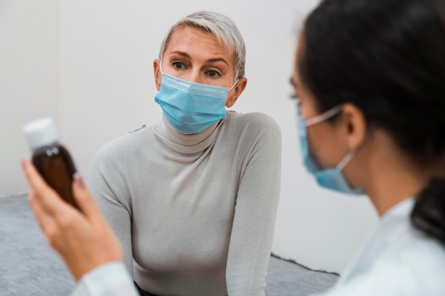 Foto gratuita doctor mostrando un frasco de medicina a un paciente