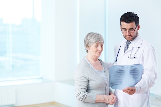 Doctor mostrando una radiografía a la paciente de edad avanzada