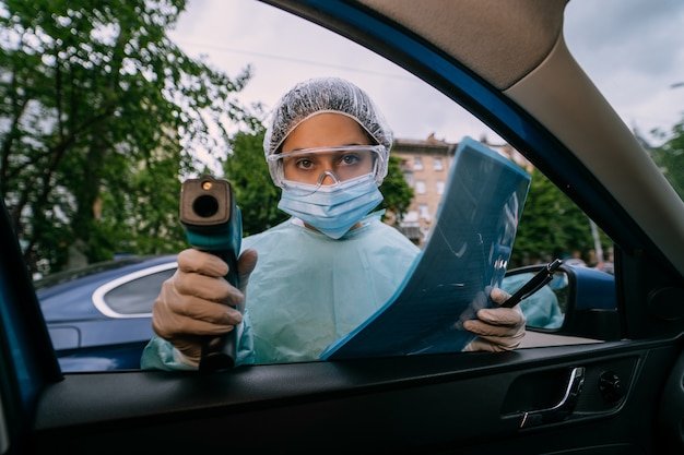 Foto gratuita doctor mujer usa pistola termómetro infrarrojo para verificar la temperatura corporal