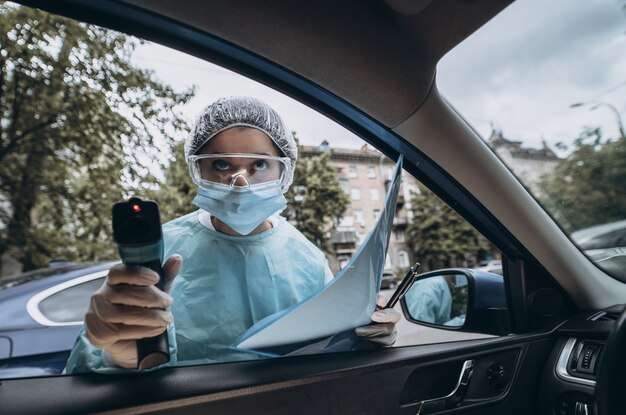 Doctor mujer usa pistola termómetro infrarrojo para verificar la temperatura corporal