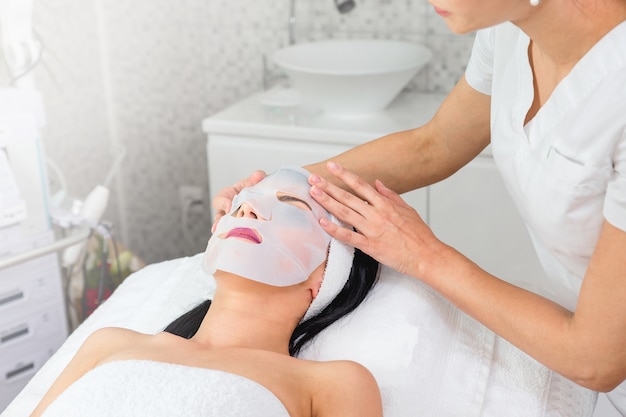 Doctor poniendo una mascarilla facial en el rostro de una mujer