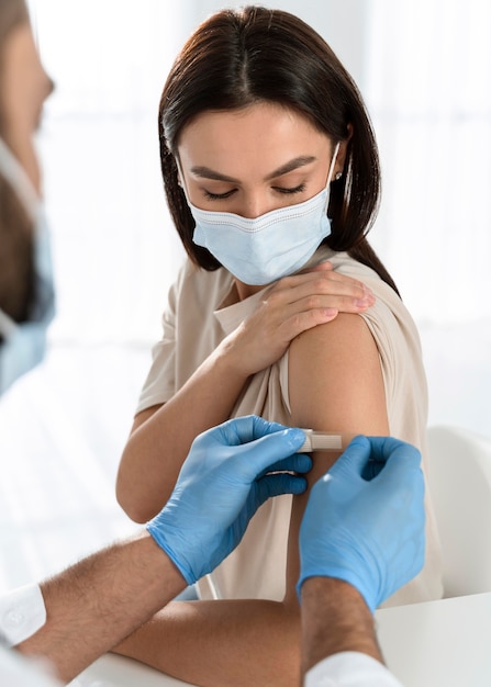 Foto gratuita doctor poniendo un vendaje en el brazo de una mujer joven