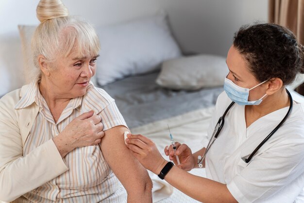 Doctor preparando la vacuna para una mujer mayor
