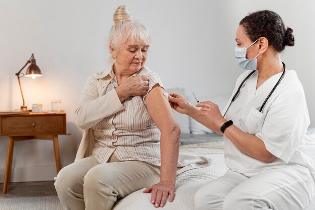 Doctor preparando la vacuna para una mujer mayor