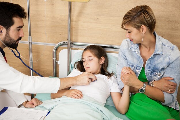 Doctor revisando su corazón paciente en la habitación del hospital