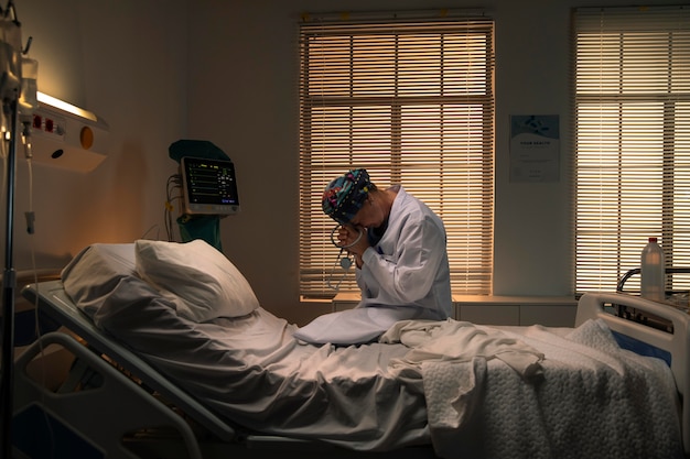 Doctor sentado en una cama de hospital mientras está triste