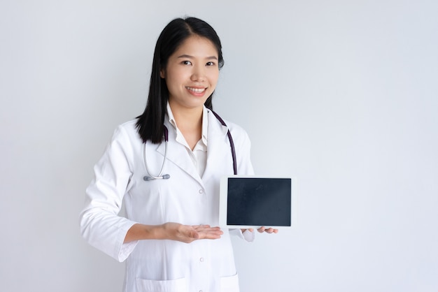 Doctor de sexo femenino feliz que muestra la pantalla de tableta