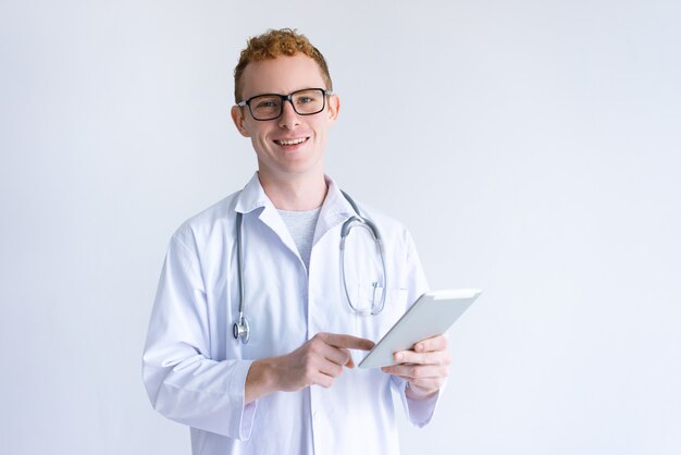 Doctor de sexo masculino joven feliz que usa la tableta