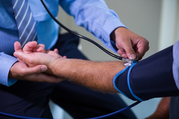 Doctor de sexo masculino que controla la presión arterial del paciente