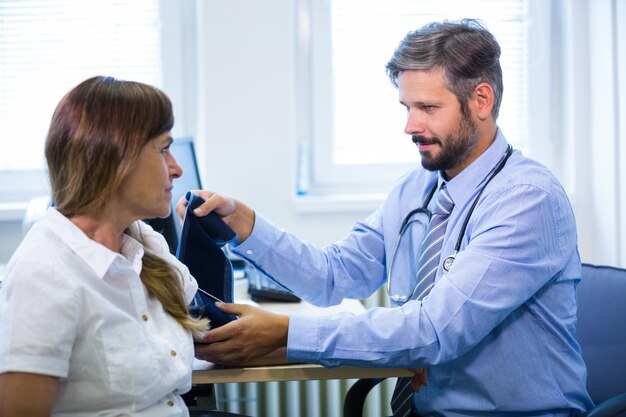 Doctor de sexo masculino que controla la presión arterial del paciente