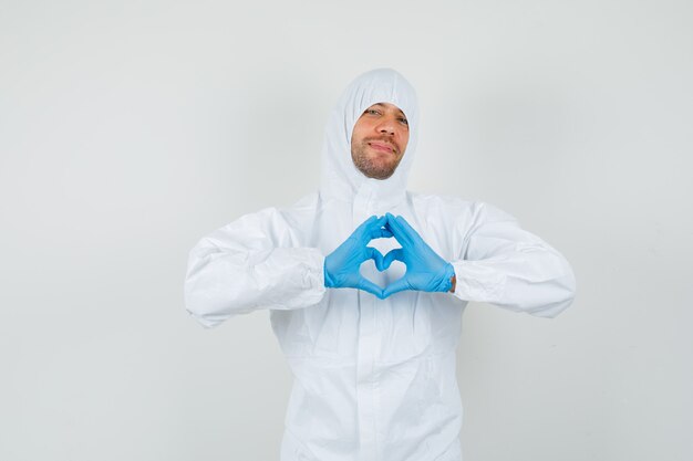 Foto gratuita doctor de sexo masculino que muestra el gesto del corazón en traje protector, guantes y mirando amado.
