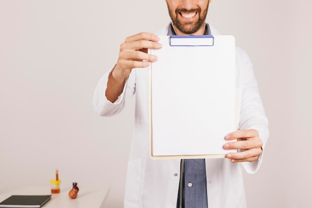 Doctor sonriendo y mostrando la información del portapapeles