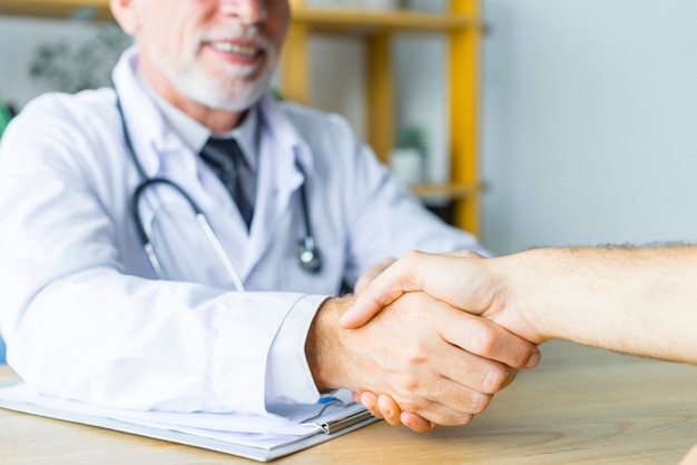 Doctor sonriente dándole la mano al paciente