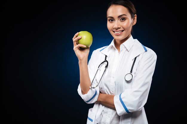 Doctor sonriente joven de la señora que sostiene la manzana y que mira