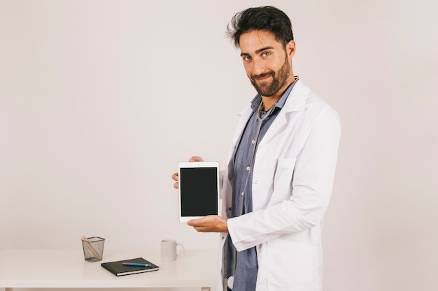 Foto gratuita doctor sonriente mostrando la pantalla de la tablet