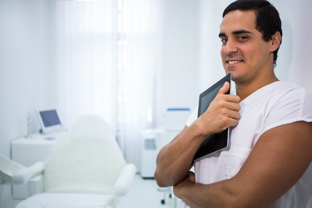 Doctor sonriente que sostiene una tableta digital en la clínica