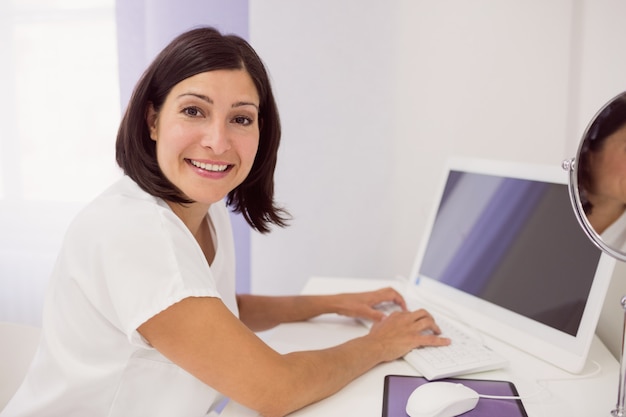 Doctor sonriente que usa la PC de escritorio