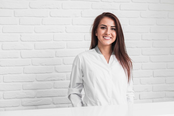 Foto gratuito doctor sonriente sentado delante de la pared de ladrillos blancos