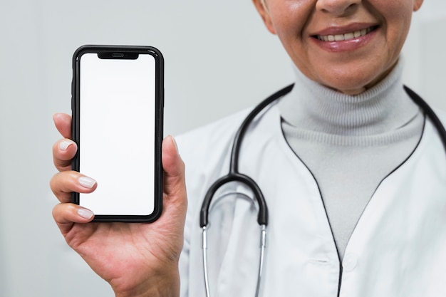 Doctor sonriente sosteniendo un teléfono en blanco