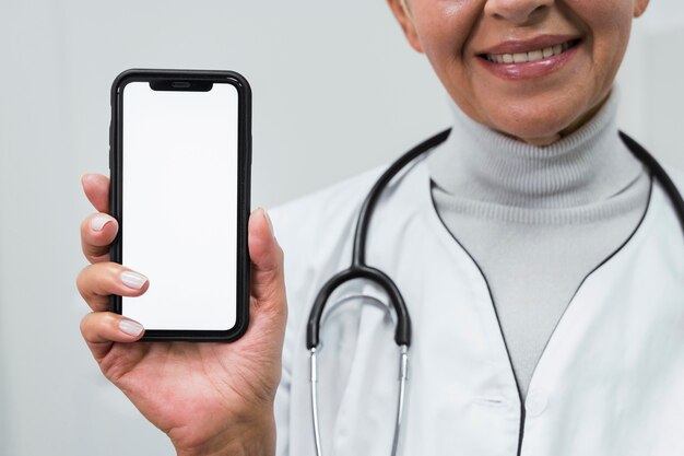 Doctor sonriente sosteniendo un teléfono en blanco