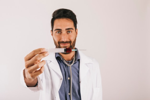 Doctor sonriente sujetando una jeringuilla