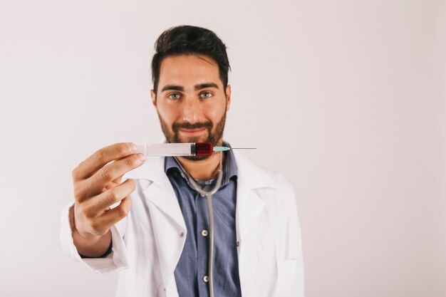 Doctor sonriente sujetando una jeringuilla