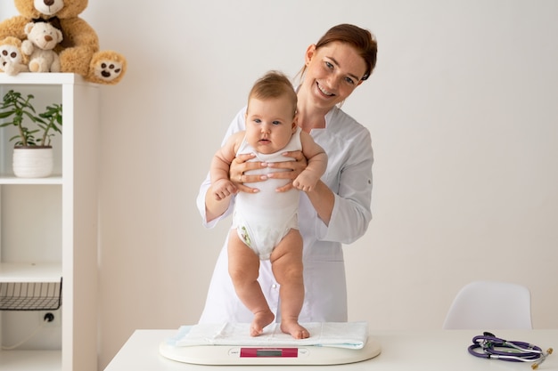 Doctor sonriente de tiro medio con bebé