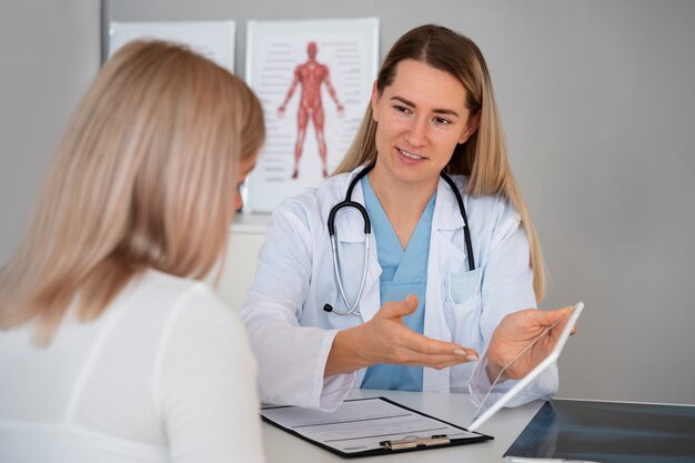 Doctor sonriente de tiro medio hablando con el paciente