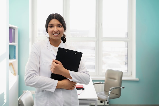 Doctor sonriente de tiro medio con portapapeles