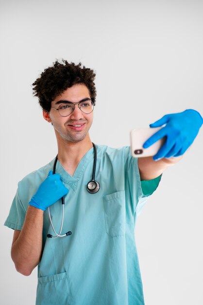 Doctor sonriente de tiro medio tomando selfie