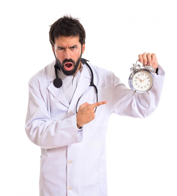 Doctor sorprendido sosteniendo un reloj sobre fondo blanco