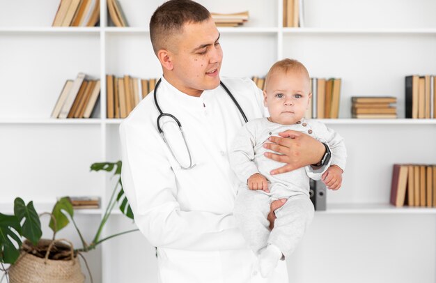 Doctor sosteniendo a un bebé y mirándolo