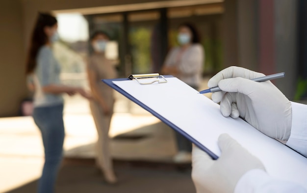 Doctor sosteniendo el bloc de notas en el centro de vacunación con pacientes al aire libre