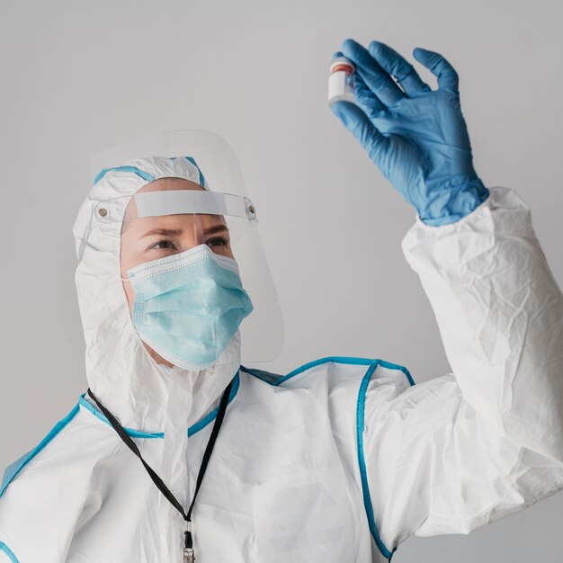 Doctor sosteniendo una botella de vacuna mientras usa equipo de protección