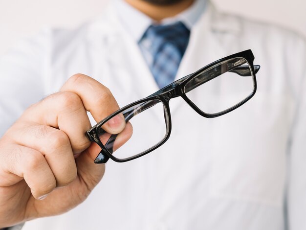 Doctor sosteniendo un par de anteojos negros