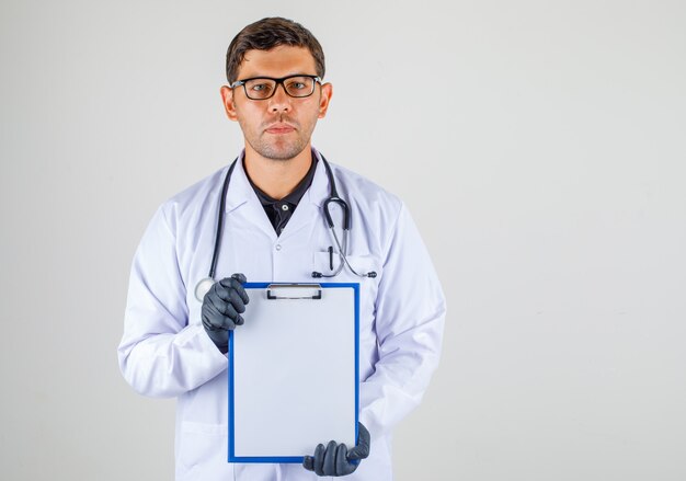 Doctor sosteniendo el portapapeles vacío en sus manos en bata blanca médica