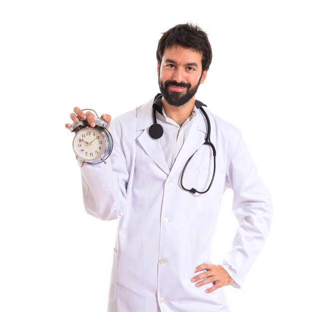 Doctor sosteniendo un reloj sobre fondo blanco