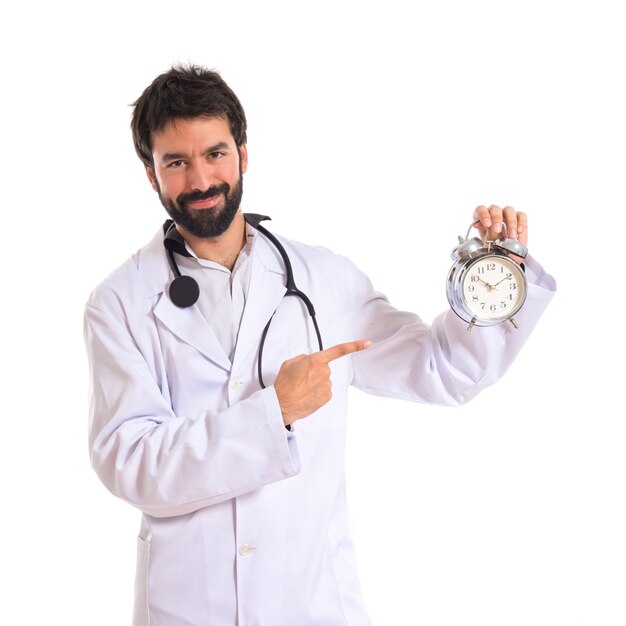 Doctor sosteniendo un reloj sobre fondo blanco