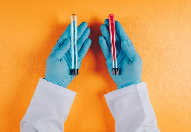 Foto gratuita doctor sosteniendo viales de laboratorio en ambas manos en naranja