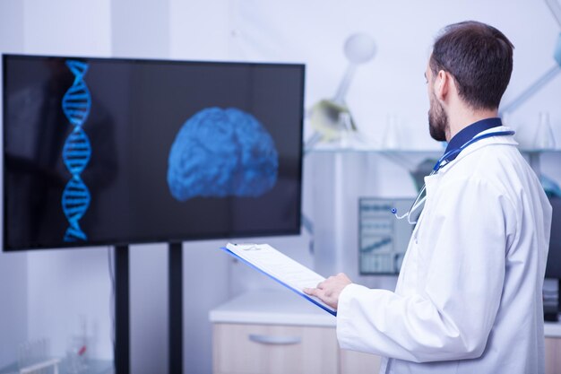 Doctor en su gabinete mirando un cerebro y tratando de dar un diagnóstico. Doctor dando su experiencia.