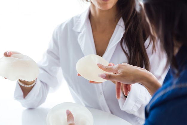 El doctor y su paciente escogiendo la prótesis mamaria en la oficina.