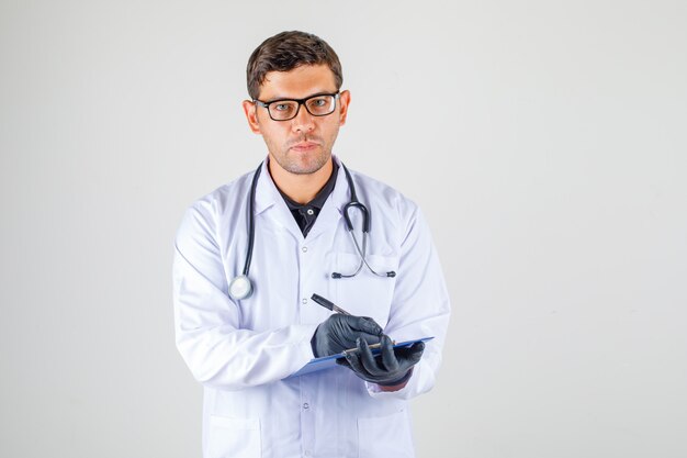 Doctor tomando notas en bata blanca médica