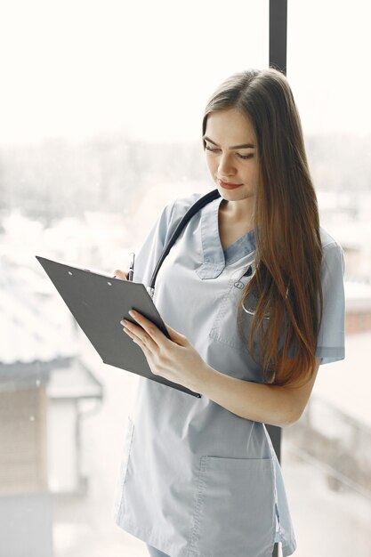 Doctor en uniforme azul. Chica con un estetoscopio alrededor de su cuello. Mujer con cabello largo.