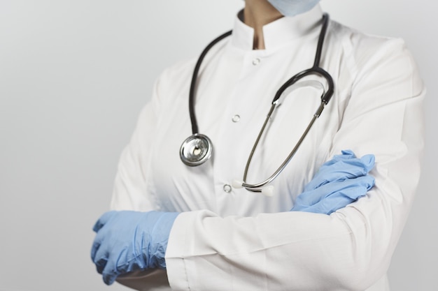 Doctor en uniforme blanco con estetoscopio de pie con los brazos cruzados