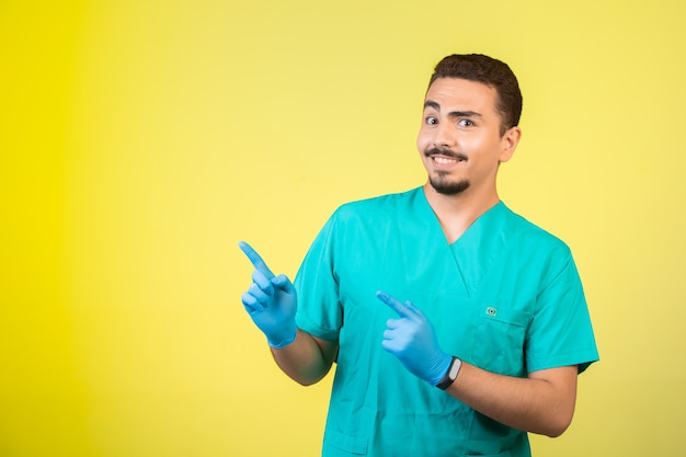 Doctor en uniforme y máscara de mano presentando algo arriba.