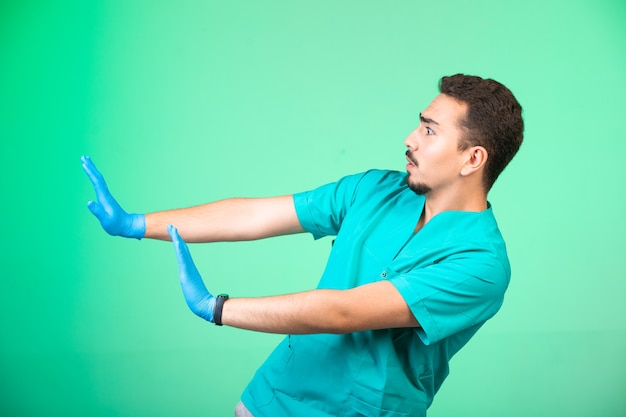 Doctor en uniforme y máscara de mano previniéndose en verde.